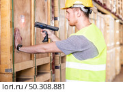 Portrait white caucasian warehouse worker use barcode reader for inventory check in large warehouse distribution center. Reopening traditional business warehouse and logistic concept. Стоковое фото, агентство Ingram Publishing / Фотобанк Лори