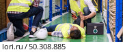 Panoramic Warehouse worker do first aid to his colleague lying down on warehouse floor after accident while working. Using for industrial safety first and business insurance concept. Стоковое фото, агентство Ingram Publishing / Фотобанк Лори