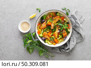 Chicken drumsticks roasted with vegetables in cast iron pan on kitchen table, top down view. Стоковое фото, агентство Ingram Publishing / Фотобанк Лори