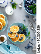 Cottage cheese pancakes, sweet curd fritters with berries, syrniki with honey and fresh blueberry on breakfast table. Стоковое фото, агентство Ingram Publishing / Фотобанк Лори