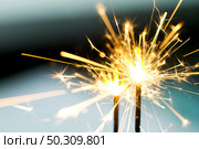 Closeup of sparks glimmering in night while fireworks burning. Стоковое фото, агентство Ingram Publishing / Фотобанк Лори