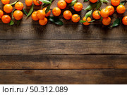 Tangerines, fresh mandarin oranges, clementines with leaves on wooden background. Top view, copy space. Стоковое фото, агентство Ingram Publishing / Фотобанк Лори