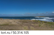 Waves are raging in the blue ocean in the strait between two islets. White foam on the surface of the water. Volcanic boulders, green grass on the shore of the island. Azure sky, clouds. Mauritius. (2024 год). Стоковое фото, фотограф Вера Ивановна Кубарева / Фотобанк Лори