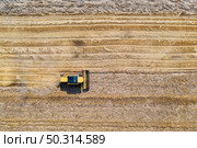 Aerial view of combine harvester is harvesting wheat at sunset in summer. Agriculture. Landscape with harvester working on the yellow wheat field. Top view of agricultural machine and ripe wheat. Стоковое фото, агентство Ingram Publishing / Фотобанк Лори