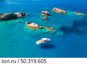 Speed boat on blue sea at sunrise in summer. Aerial view of motorboat on sea bay, rocks in clear azure water. Tropical landscape with yacht, stones. Top view from drone. Travel in Oludeniz, Turkey. Стоковое фото, агентство Ingram Publishing / Фотобанк Лори