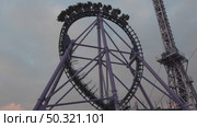 Rollercoaster Loop, Amusement Park, Ride: Thrill-seeking passengers experience a large loop on a purple rollercoaster during daytime. Стоковое видео, видеограф svetograph / Фотобанк Лори