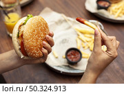 high angle person eating burger french fries. Стоковое фото, агентство Ingram Publishing / Фотобанк Лори