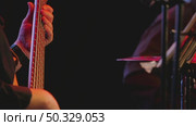 A close-up of a musician's hand deftly clasping the strings on a bass guitar fingerboard, illuminated by a bright stage light against a dark background. Стоковое видео, видеограф Воловодов Владимир / Фотобанк Лори