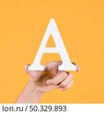 human hand holding up uppercase capital letter yellow background. High resolution photo. human hand holding up uppercase capital letter yellow background. High quality photo. Стоковое фото, агентство Ingram Publishing / Фотобанк Лори