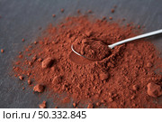 From above of teaspoon placed on heap of bitter cocoa powder of dark brown color on gray background. Organic dry cocoa powder pile. Стоковое фото, агентство Ingram Publishing / Фотобанк Лори