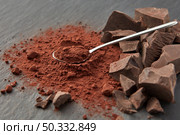 Arranged shiny teaspoon on pile of dry cocoa powder and heap of organic chocolate pieces on gray surface. Chunks of chocolate and cocoa powder. Стоковое фото, агентство Ingram Publishing / Фотобанк Лори