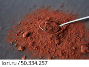 From above of teaspoon placed on heap of bitter cocoa powder of dark brown color on gray background. Organic dry cocoa powder pile. Стоковое фото, агентство Ingram Publishing / Фотобанк Лори