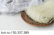 dried rice vermicelli noodles circular plate near checkered cloth white surface. Стоковое фото, агентство Ingram Publishing / Фотобанк Лори