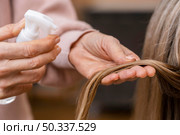 hairdresser holding tuft hair spraying with water. Стоковое фото, агентство Ingram Publishing / Фотобанк Лори