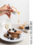 hand pouring honey toast with blueberries. Стоковое фото, агентство Ingram Publishing / Фотобанк Лори