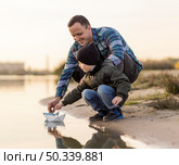 father son playing with origami boat. Стоковое фото, агентство Ingram Publishing / Фотобанк Лори