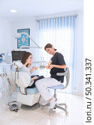 female dentist showing teeth model smiling patient clinic. Стоковое фото, агентство Ingram Publishing / Фотобанк Лори