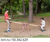 brothers playing seesaw. Стоковое фото, агентство Ingram Publishing / Фотобанк Лори