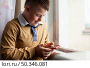 side view boy with down syndrome holding smartphone. Стоковое фото, агентство Ingram Publishing / Фотобанк Лори