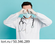 front view doctor with medical mask rubbing his eyes. Стоковое фото, агентство Ingram Publishing / Фотобанк Лори
