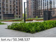 Двор в ЖК Вереск. Contemporary Urban Living: Landscaped Courtyard of Modern Residential Buildings with Greenery and Paved Walkways. Ideal for real estate development or architectural publication. Стоковое фото, фотограф Данила Большаков / Фотобанк Лори