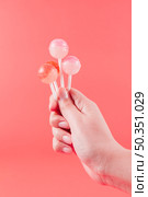 close up woman s hand holding lollipops against coral backdrop. Стоковое фото, агентство Ingram Publishing / Фотобанк Лори