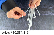 Hands holding plastic cable ties over a textured surface, showcasing tool preparation. Стоковое фото, фотограф Анастасия / Фотобанк Лори