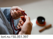 high angle woman holding beads meditating. Стоковое фото, агентство Ingram Publishing / Фотобанк Лори