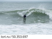 Bodyboarder surfing ocean wave on a cloudy winter day. Стоковое фото, агентство Ingram Publishing / Фотобанк Лори