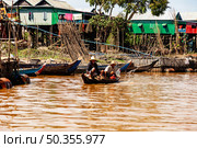 Life on Tonle Sap Lake Two Cambodian Men Fish From a Boat (2014 год). Редакционное фото, фотограф Aleksandr Golubev / Фотобанк Лори