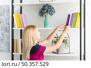 woman choosing book from shelf home. Стоковое фото, агентство Ingram Publishing / Фотобанк Лори