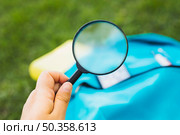 holding magnifier increases background backpack grass. Стоковое фото, агентство Ingram Publishing / Фотобанк Лори