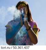 young woman dusting blue holi color with hands. Стоковое фото, агентство Ingram Publishing / Фотобанк Лори