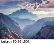 Mountain canyon lighted by bright sunbeams at sunset in autumn in Dolomites, Italy. Landscape with mountain ridges, rocks, colorful trees and orange grass, alpine meadows, gold sunlight in fall. Alps. Стоковое фото, агентство Ingram Publishing / Фотобанк Лори