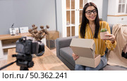 female vlogger home with camera unboxing plant. Стоковое фото, агентство Ingram Publishing / Фотобанк Лори