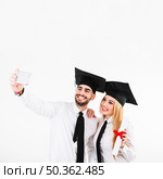 graduating couple mortarboards taking selfie. Стоковое фото, агентство Ingram Publishing / Фотобанк Лори