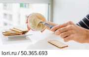 close up woman applying cheese spread bread with knife white table. Стоковое фото, агентство Ingram Publishing / Фотобанк Лори