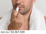 young stubble man with white towel applying balm lips. Стоковое фото, агентство Ingram Publishing / Фотобанк Лори