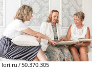senior woman looking album with her daughter grand daughter. Стоковое фото, агентство Ingram Publishing / Фотобанк Лори