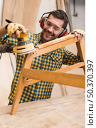 smiling male carpenter softening edges wooden furniture with sander. Стоковое фото, агентство Ingram Publishing / Фотобанк Лори