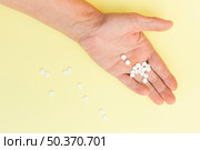 white round tablets hand person against yellow background. Стоковое фото, агентство Ingram Publishing / Фотобанк Лори