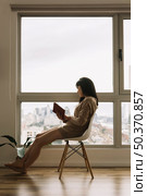 young woman reading near huge window. Стоковое фото, агентство Ingram Publishing / Фотобанк Лори