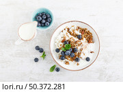 Bowl of granola with fresh blueberry, cottage cheese or curd, yogurt and nuts. Healthy food. Breakfast. Top view. Стоковое фото, агентство Ingram Publishing / Фотобанк Лори