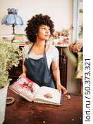 african female florist with flower album shop. Стоковое фото, агентство Ingram Publishing / Фотобанк Лори