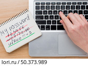 flat lay laptop with hands notebook with password information. Стоковое фото, агентство Ingram Publishing / Фотобанк Лори