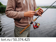 man s hand holding fishing lure rod. Стоковое фото, агентство Ingram Publishing / Фотобанк Лори