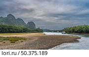 Tourist ships sail along the picturesque river. The riverbed bends. Foam on the pebbly shores. Lush green vegetation. Mountains against the sky and clouds. China. Li River. Li Jiang. Guilin. Стоковое фото, фотограф Вера Ивановна Кубарева / Фотобанк Лори
