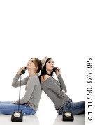Two young women talking with old telephones - Isolated on white. Стоковое фото, агентство Ingram Publishing / Фотобанк Лори