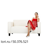 Beautiful woman seated on a white couch biting her nails (with frightened and suspicious espression) Стоковое фото, агентство Ingram Publishing / Фотобанк Лори