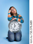 Beautiful women over knees holding a big clock with a blue background. Стоковое фото, агентство Ingram Publishing / Фотобанк Лори